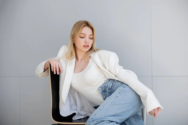 Veste élégante jeune femme assise sur une chaise à la maison — Photo de stock