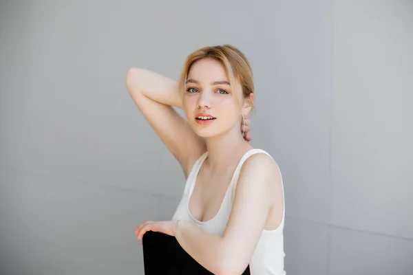 Young woman touching neck while sitting on chair at home — Stock Photo