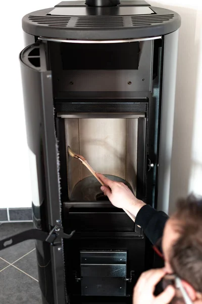 Man cleaning pellet stove with brush, talking on mobile phone, professionnal work