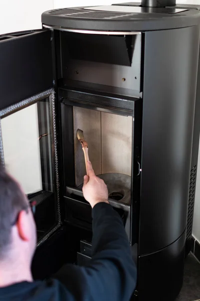 Man cleaning pellet stove with brush