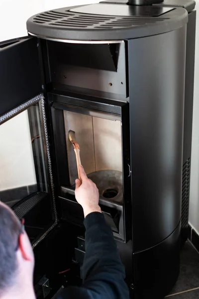 Man cleaning pellet stove with brush