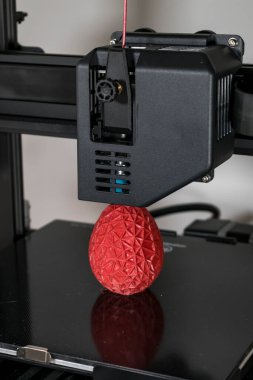 Close up of a 3d printer printing a red polygonal egg