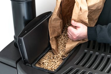 Man loading pellet stove with granule bag