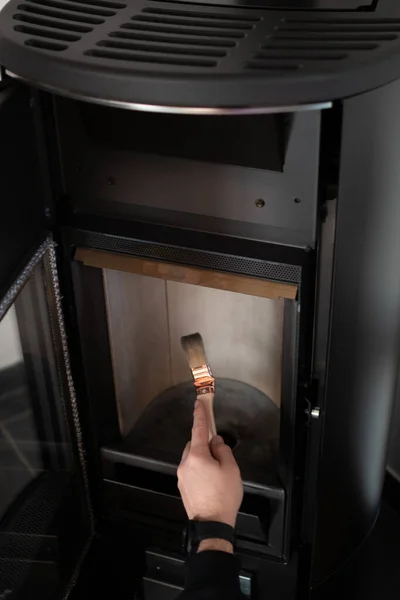 Man cleaning pellet stove with brush