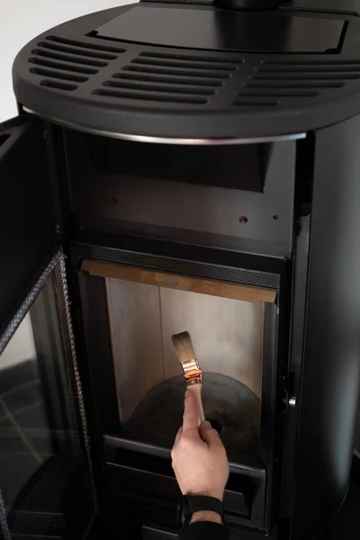 Man cleaning pellet stove with brush