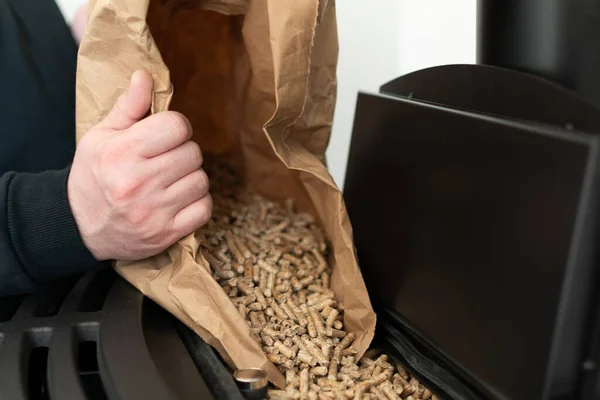 Man loading pellet stove with granule bag