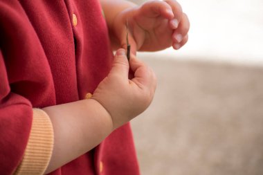 close up of a baby's hands playing with a twig, outside activity, fine motor skills development