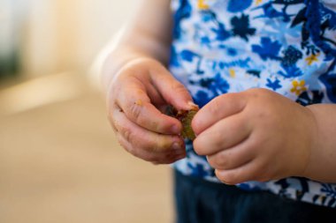 close up of a baby's hands opening a fruit, outside activity, fine motor skills development