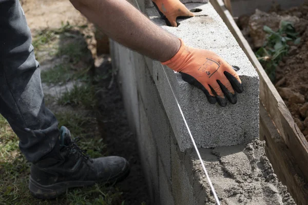 Bricklayer in glove spreading concrete to build a wall on construction site
