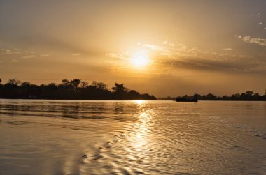 Gün batımında Gambiya nehrinde bir feribotun silueti.