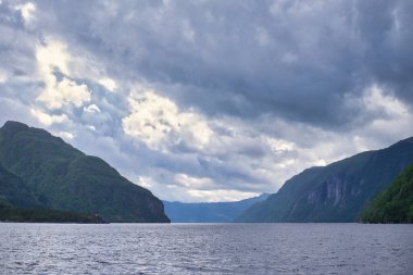 Güneş ve bulutlar Norveç fiyordunun üzerinde savaşıyor