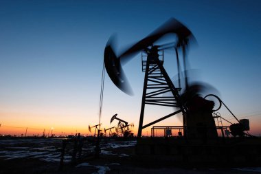 Petrol sahalarındaki petrol pompaları akşamları çalışıyor. Gün batımında da petrol pompalarının siluetleri.