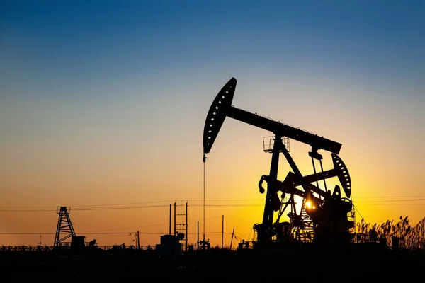 The oil pumps in the oil fields are working in the evening, Silhouettes of oil pumps at sunset