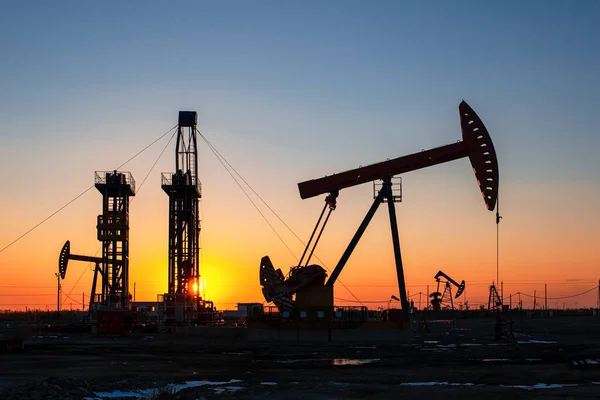 The oil pumps in the oil fields are working in the evening, Silhouettes of oil pumps at sunset