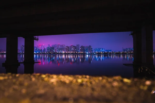 Colorful Night Cityscape Buildings with River Reflections under the Bridge