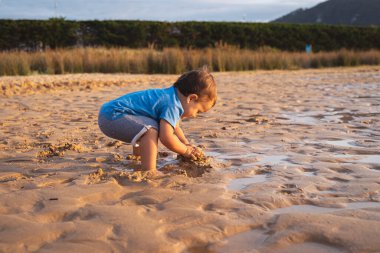 Küçük çocuk kumsalda oynuyor.