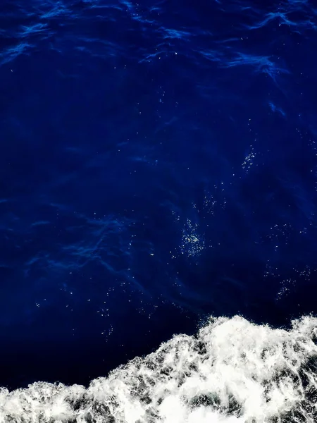 Softfocused indigo azul mar águas superfície e espuma branca do navio. Abstrato cores brilhantes naturais fundo. Viajar de barco. Mar Jónico, Grécia. — Fotografia de Stock