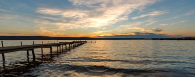 Sahilde heyecanlı bir alacakaranlık bayrağı ve ahşap bir iskele.