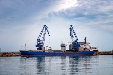 Liman şehrinin ticaret gemisi vinçlerle malzeme yüklemeye hazır..