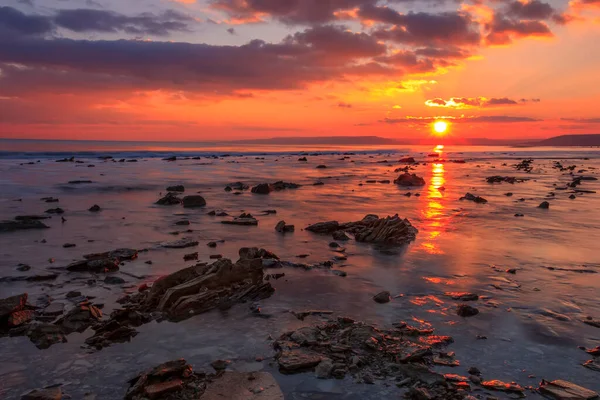 Sunning long exposure sunset over the sea with a rocky beach.