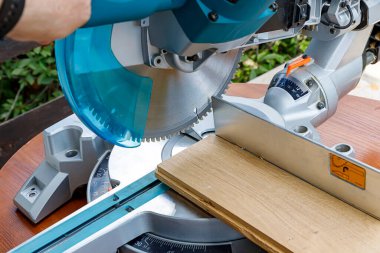 Miter saw in the process of sawing off a wooden part. Close up