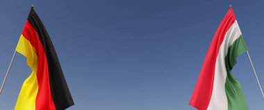 Mavi arka planda bayrak direkleri üzerinde Almanya ve Macaristan bayrakları. Mesaj için yer. Rüzgarda dalgalanan bayraklar. Alman, Berlin. Macarca, Budapeşte. 3d illüstrasyon.