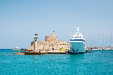 Mandraki limanının girişindeki Agios Nikolaos Kalesi (Aziz Nikolaos Kalesi) ve ön plandaki sütundaki geyik heykeli.
