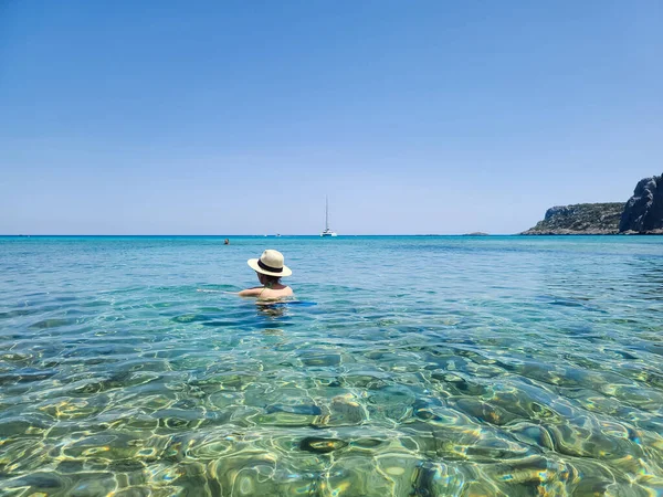 Hasır şapkalı kız Yunanistan 'ın Rodos adasındaki Navarone Koyu' nda yüzüyor.