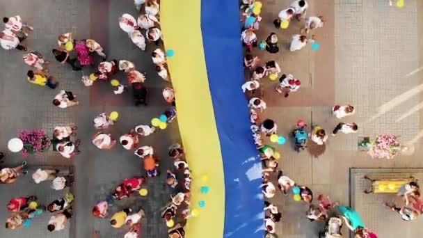 サムイ島でウクライナの巨大な旗を持つ多くの人々のドローンショット 街の中心部に巨大なウクライナの看板 ドローンビュー ウクライナ独立記念日 英語版 — ストック動画
