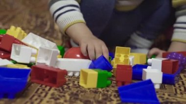 Çocuk oyuncaklarla oynanır. Küçük çocuk inşaatçıyı yatağa monte ediyor. Çok renkli oyuncaklar. Küçük bebek detayları. Bebeğin evde kendi kendini tecrit etmesi. Renkli çocuk çorapları ve taytları