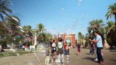 Çocuklar ve ebeveynler Barselona 'da bir parkta dinleniyorlar. Çocuklar anne babalarıyla sabun köpüğüyle oynarlar. Barcelona 'daki Zafer Takı anıtı. Barcelona 'daki Ciutadella Parkı