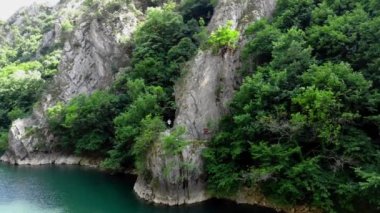 Matka Kanyonu 'nun insansız hava aracı görüntüsü. Kuzey Makedonya 'da bir gölün insansız hava aracı görüntüsü. Rocky yeşil yamaçları. Gölün şeffaf su yüzeyi. Nehir boyunca dağ yolu. Dağlarda göl