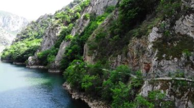 Matka Kanyonu 'nun insansız hava aracı görüntüsü. Kuzey Makedonya 'da bir gölün insansız hava aracı görüntüsü. Rocky yeşil yamaçları. Gölün şeffaf su yüzeyi. Nehir boyunca dağ yolu. Dağlarda göl