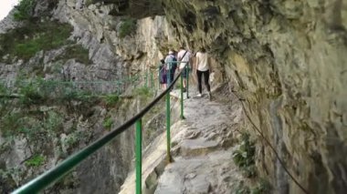 İnsanlar Matka Kanyonu 'nda bir dağ yolunda yürüyor. Vadi boyunca dağ yolu. Matka Üsküp Kanyonu. Kuzey Makedonya 'daki kanyon. Treska Nehri Vadisi. Yeşil kayalık yamaçlar.