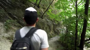Genç bir adam Matka Kanyonu 'nda dağ yolunda yürüyor. Vadi boyunca dağ yolu. Matka Üsküp Kanyonu. Kuzey Makedonya 'daki kanyon. Yeşil kayalık yamaçlar