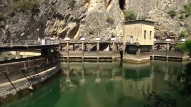 Matka Üsküp Kanyonu. Kuzey Makedonya 'daki kanyon. Treska Nehri Vadisi. Yeşil kayalık yamaçlar. Turkuaz suyu olan temiz bir göl. Matka Kanyonu 'ndaki hidroelektrik santrali. Kanyonun panoramik görüntüsü