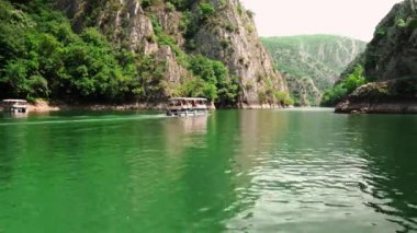 Matka Üsküp Kanyonu. Kuzey Makedonya 'daki kanyon. Treska Nehri Vadisi. Tekne gezisi. Yeşil kayalık yamaçlar. Şeffaf Matka Gölü ve turkuaz su. Kanyonun panoramik görüntüsü