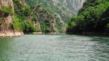Matka Üsküp Kanyonu. Kuzey Makedonya 'daki kanyon. Treska Nehri Vadisi. Tekne gezisi. Yeşil kayalık yamaçlar. Şeffaf Matka Gölü ve turkuaz su. Kanyonun panoramik görüntüsü