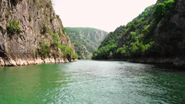 Matka Üsküp Kanyonu. Kuzey Makedonya 'daki kanyon. Treska Nehri Vadisi. Tekne gezisi. Yeşil kayalık yamaçlar. Şeffaf Matka Gölü ve turkuaz su. Kanyonun panoramik görüntüsü