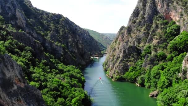 Matka峡谷的Drone视图 在马其顿北部的峡谷里 无人机拍摄了一个湖中的照片 岩石绿色斜坡 小船沿着峡谷河航行 沿河的山路 山中的湖 — 图库视频影像