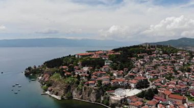 Drone view of the resort town of Ohrid. Drone shot overlooking Lake Ohrid and a small town against the backdrop of green mountains. A pier with boats in the center of Ohrid, a view from above.