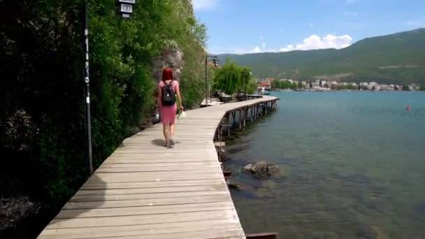 马其顿北部奥赫里德市 一个女孩沿着岩石穿过奥赫里德湖 沿着一条小径走着 奥赫里德湖东岸的一座城市 巴尔干最深 最古老的湖泊 — 图库视频影像