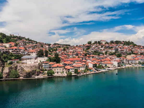 Ohri tatil beldesinin insansız hava aracı görüntüsü. Ohri Gölü 'ne ve yeşil dağların arkasına bakan küçük bir kasabaya bakan insansız hava aracı vuruldu. Ohri 'nin merkezinde tekneleri olan bir iskele, yukarıdan bir manzara..
