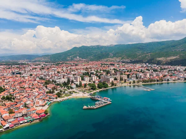 Ohri tatil beldesinin insansız hava aracı görüntüsü. Ohri Gölü 'ne ve yeşil dağların arkasına bakan küçük bir kasabaya bakan insansız hava aracı vuruldu. Ohri 'nin merkezinde tekneleri olan bir iskele, yukarıdan bir manzara..