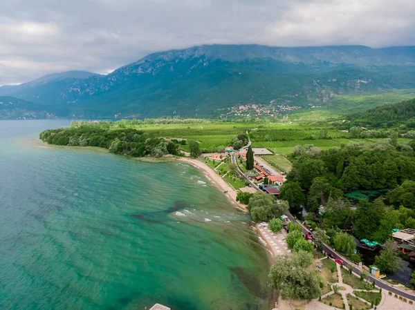 Ohri Gölü kıyısındaki kafe ve restoranların insansız hava aracı görüntüleri. Makedonya 'daki yeşil dağların insansız hava aracı manzarası. Makedonya 'nın kuzeyindeki Ohri Gölü' nün kumlu plajı.