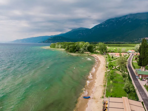 Ohri Gölü kıyısındaki kafe ve restoranların insansız hava aracı görüntüleri. Makedonya 'daki yeşil dağların insansız hava aracı manzarası. Makedonya 'nın kuzeyindeki Ohri Gölü' nün kumlu plajı.