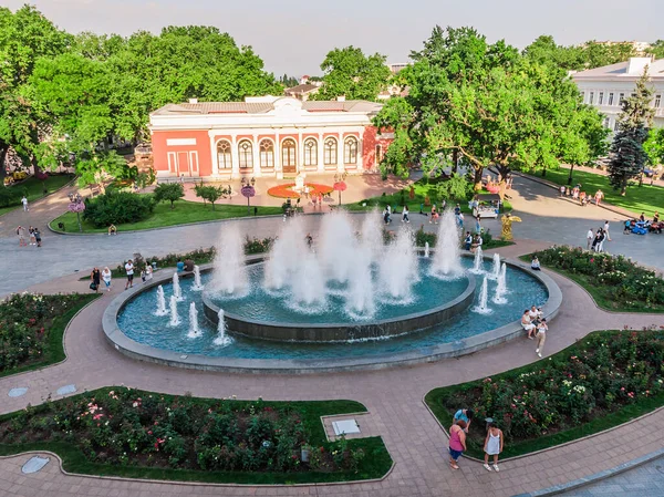 İnsansız hava aracı çekimleri Odessa Opera ve Bale Tiyatrosu 'nun çeşmesinin yanında dinleniyor. İnsanlar Odessa 'daki bir çeşmenin arka planında fotoğraflanıyor. Çiçek yatakları