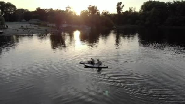 青い湖の上のサブボードに浮かぶ人々のドローンビュー 暑い日にはボードに乗って湖に浮かぶのも楽しいですよね 川の上で休憩 時間をお楽しみください 大きな湖でドローンが撃たれた — ストック動画