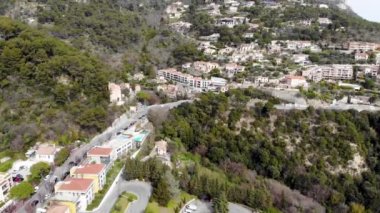 Nice civarındaki Fransız Rivierası 'ndaki Eze şehrinin insansız hava aracı panoramik görüntüsü. Alpler. Denize yakın bir uçurumun kenarındaki şehir bir dron ile filme alındı. Ortaçağ şehri. Araba trafiği yolda..