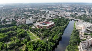 Sumy şehrindeki bir futbol stadyumunun insansız hava aracının panoramik görüntüsü. Kuzey Avrupa 'da bir stadyum. Ukrayna 'da bir şehir ve nehirdeki bir drondan bir atış. Dönme dolaba sahip yeşil park.